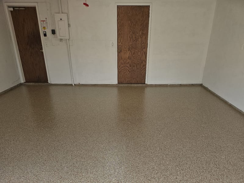 The same Wayzata garage floor finished in Hickory decorative flake, covering wall to wall with a coved edge where the floor meets the wall